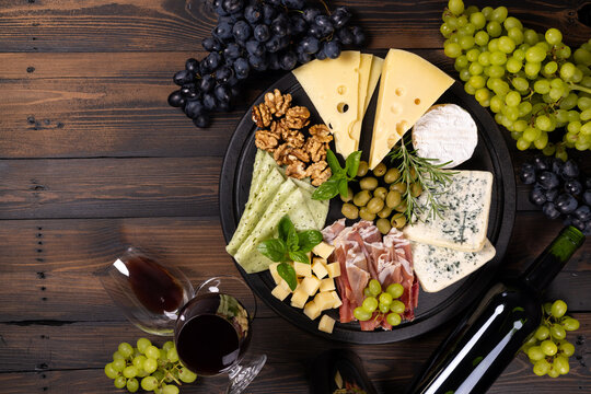 Charcuterie board with cheese, grapes, wine and prosciutto