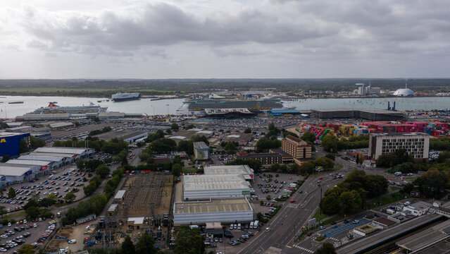 Aerial view of the port of Southampton with cruise ships docked at the terminal, industrial buildings, parking lots, and roads in Southampton, England, United Kingdom.