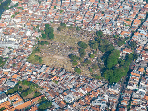 Aerial view of a cemetery surrounded by dense urban housing and lush trees in Surabaya, East Java, Indonesia.