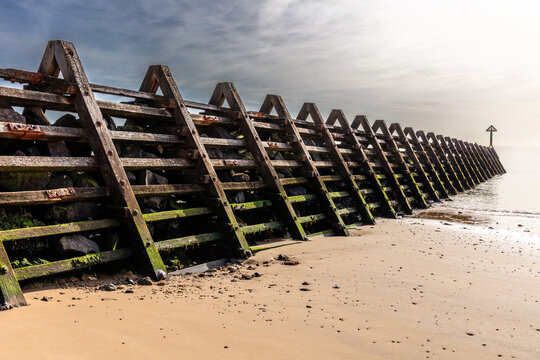 Wooden and concrete groynes are used along the beach at Walton-on-the-Naze as a form of hard coastal engineering to stop longshore drift and reduce beach erosion. Shot 21 September 2026.