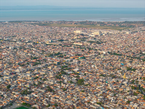 Aerial view of the dense urban landscape with its sprawling residential rooftops and coastal proximity in Surabaya, East Java, Indonesia.