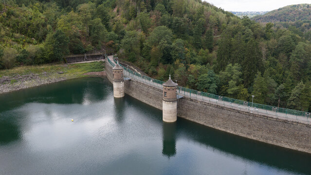 Aerial view of Sengbachtalsperre dam with its stone towers and reservoir surrounded by dense forest in Solingen, Nordrhein-Westfalen, Germany.