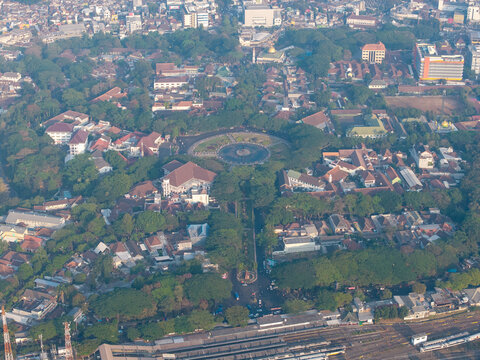 Aerial view of Alun-Alun Malang surrounded by lush trees, historic buildings, and urban streets in the city center of Malang, East Java, Indonesia.