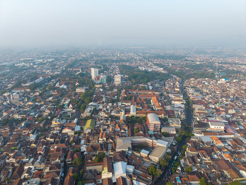 Aerial view of the dense urban landscape with its terracotta rooftops, winding streets, and hazy atmosphere in Malang, East Java, Indonesia.