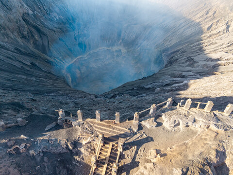 Aerial view of the Mount Bromo crater rim with stone stairs and railings overlooking the volcanic landscape in the morning light in Tosari, East Java, Indonesia.