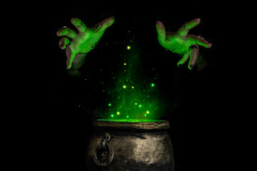 Fototapeta na wymiar Witch's hands over a cauldron with a magic potion in a dark room. Witch casting spells on Halloween night