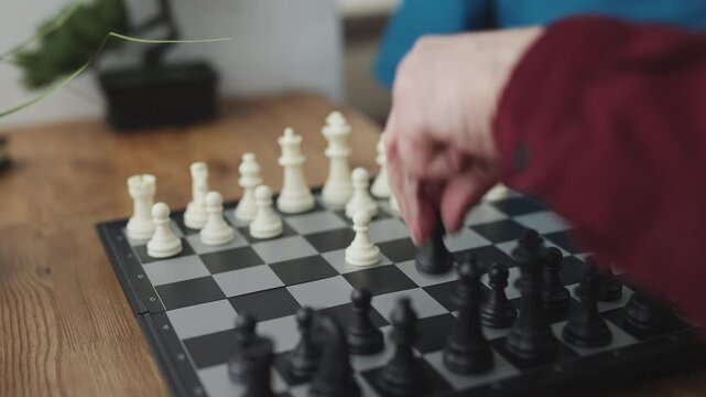 Female carer playing chess with elderly man, memory training for seniors