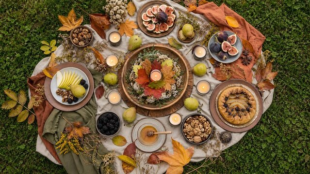 Top view of autumn equinox picnic with fruit pie candles and leaves