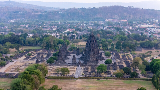 Aerial view of Prambanan Temple, an ancient Hindu temple complex with towering stone spires surrounded by lush greenery and the town of Kecamatan Prambanan, Daerah Istimewa Yogya, Indonesia.