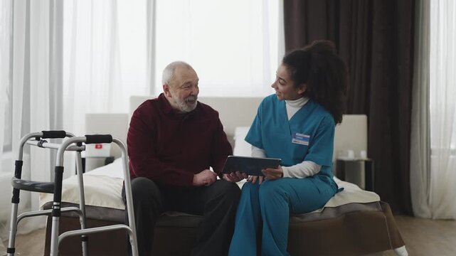 Kind nurse helping senior man create social media account using tablet