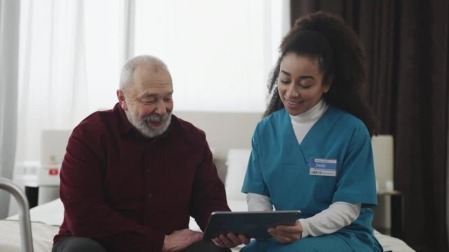 African American nurse helping elderly man install banking app on tablet