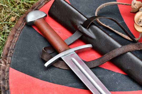 Medieval sword with leather scabbard on a red and black shield