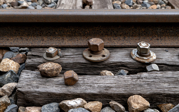 Close-up of train track rail and wooden sleeper with bolts and rocks