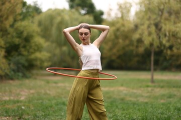 Athletic young woman exercising with hula hoop in park © New Africa