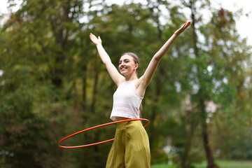 Athletic young woman exercising with hula hoop in park © New Africa