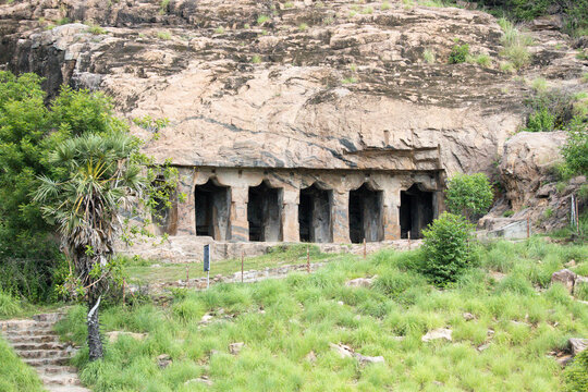 Impressive view of a historic rock-cut cave temple and ancient rock-cut architecture in Tamil Nadu, South India. The intricately carved stone structures, pillars, and sanctums are seen.