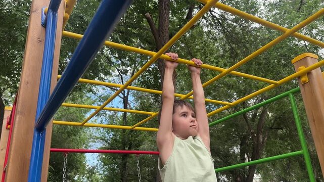 Young child climbing and playing on monkey bars at an outdoor playground. Active childhood, outdoor recreation, exercise and physical activity. 