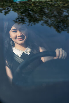 Beautiful young woman smiling while driving a car