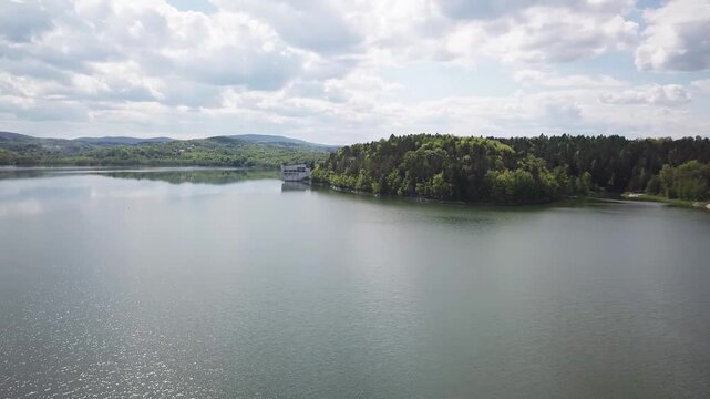 Shore of water reservoir with forest under blue sky at sunny summer day. Aerial view.