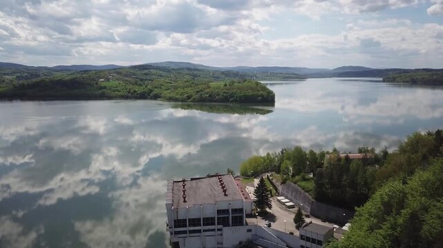 Shore of water reservoir with forest under blue sky at sunny summer day. Aerial view.