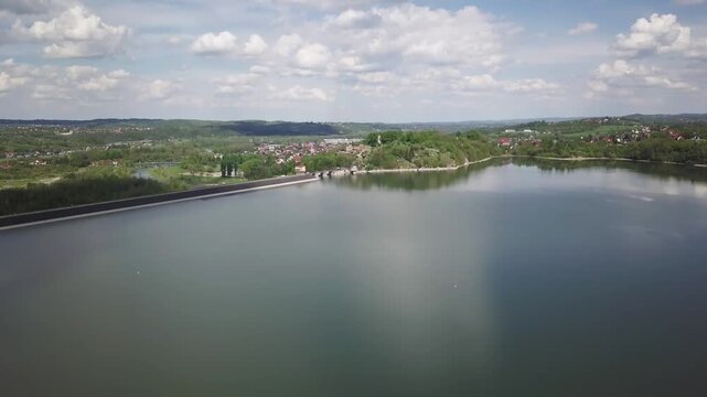 Shore of water reservoir with forest under blue sky at sunny summer day. Aerial view.