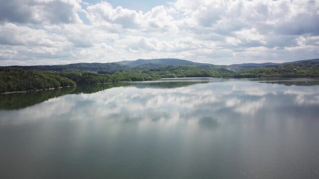 Shore of water reservoir with forest under blue sky at sunny summer day. Aerial view.