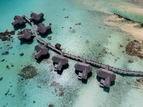 Tikehau, French Polynesia - 11 September 2026: Aerial view of Le Tikehau by Pearl Resorts with overwater bungalows connected by a wooden walkway over the turquoise lagoon.