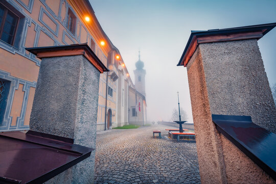 Marvelous autumn scene of Frauenberg an der Enns Catholic church, Austria, Europe. Foggy morning view of medieval Austrian backyard. Traveling concept background.