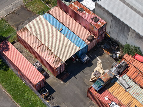 Kilsyth, Victoria, Australia - 20 September 2026: Aerial view of shipping containers stacked in an industrial yard with weathered metal surfaces and surrounding factory buildings.