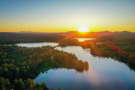 Sunset in early Autumn over Fish Creek Bay NY Adirondacks with vibrant fall foliage aerial drone