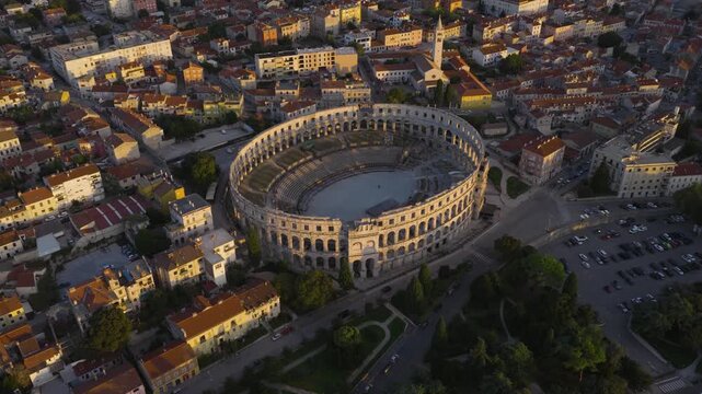 Aerial view of the ancient Roman amphitheater Pula Arena surrounded by historic buildings and urban streets in Pula, Istria County, Croatia.