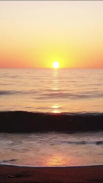 Sunset ocean waves rolling onto sandy beach with glowing golden sunlight reflection in motion video
