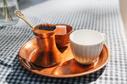 Served on a copper tray - traditional Turkish coffee set with cezve, ornate cup, and lokum. Cafe culture concept.