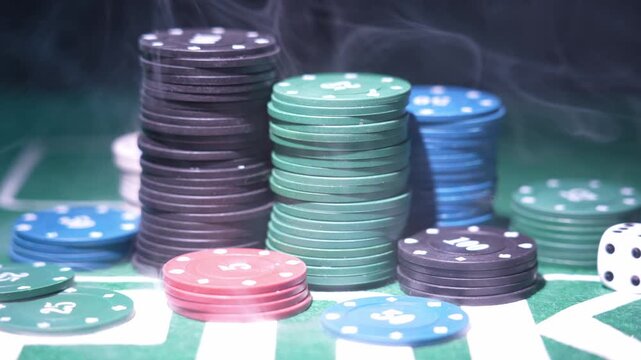 Close-up shot of assorted poker chips stacked in neat piles. Colors include black, green, blue, and red. Blurred green background suggests casino setting. Perfect for gambling or finance concepts