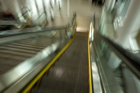 Intentional motion blur as moving down an escalator with bright yellow lines
