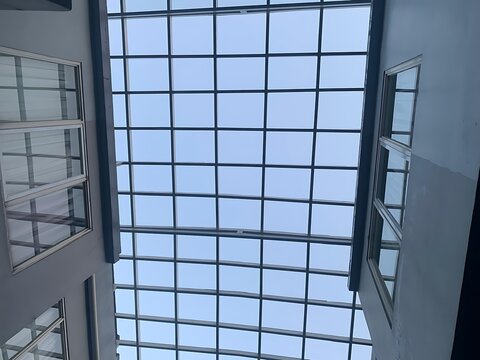 Modern glass skylight roof structure over a building interior corridor.