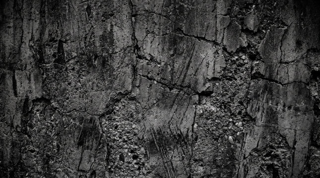 Grungy dark concrete wall texture backgrounds with extensive cracks and exposed aggregate offering a rugged industrial texture background for design projects