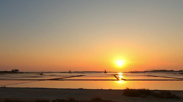 Golden sunset over tranquil salt pans near Trapani, Italy