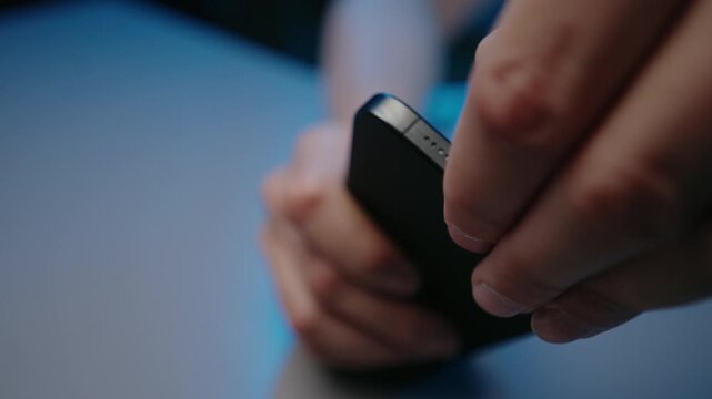 Person cleaning dust from smartphone charging port using small tool for device maintenance, preventing connection issues and ensuring proper battery charging and data transfer, close-up, slow motion.