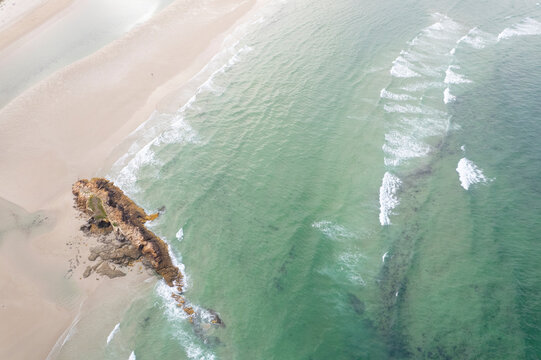Aerial view of rocky reef on sandy beach with turquoise sea The Concept of coastal wilderness