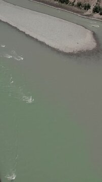 Drone footage of the confluence of the Chuya and Katun rivers with turquoise water, gravel banks and arid hills in Altai Republic, Russia