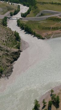 Drone footage of the confluence of the Chuya and Katun rivers, with bridge, gravel banks and steppe landscape near Inya, Altai Republic, Russia