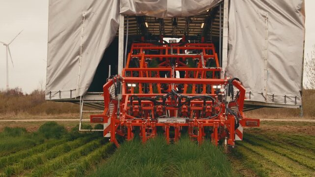 text translation: attention. machine for harvesting grass herb green onion from field in action. close-up mechanized process of cutting green onions. sharp bladed knives pick onions. harvester use and