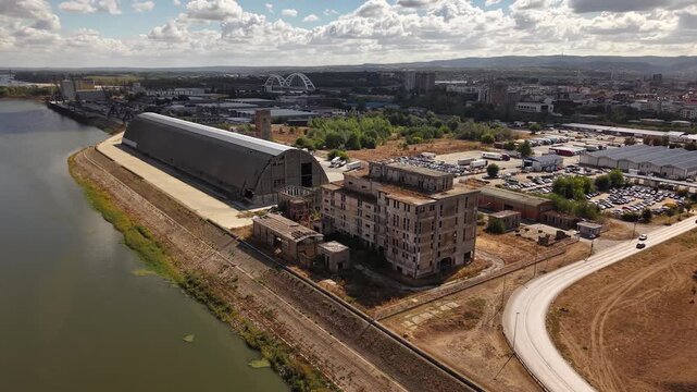 Wide aerial view of abandoned factory complex beside canal