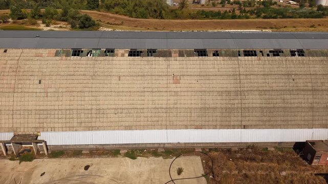 Aerial tracking shot over weathered roof of abandoned factory
