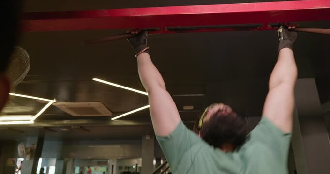 An Indian male athlete performs strict pull-ups on a pull-up bar in a modern gym. He uses controlled bodyweight movements to build back, shoulder, and arm strength
