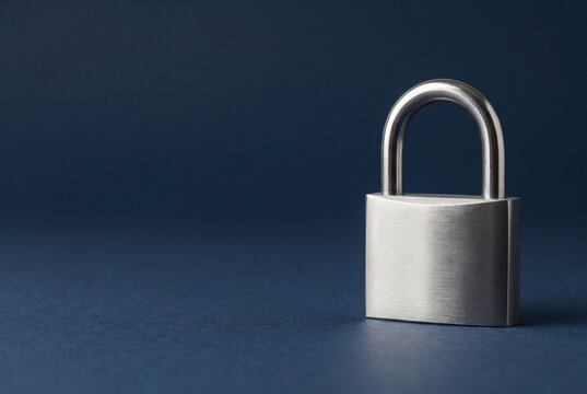 Closed metal padlock on dark blue background with copy space