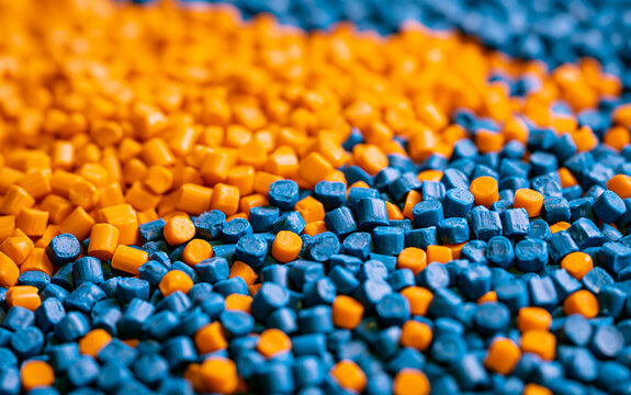 Close up of blue, orange plastic granules. Colorful polymer resin pellets pile up for industrial injection moulding process. Raw thermoplastic material beads used in manufacturing production