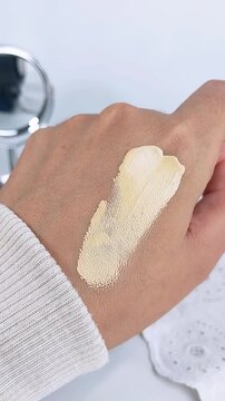 Point of view of swatching or smearing mocha cream liquid onto hand skin. Cushion makeup try on concept, cosmetic product test for beauty routine.