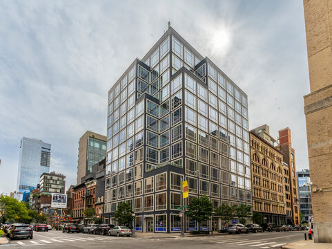 New York, NY - US - Sep 25, 2026 : Glass House in Hudson Square features its modern glass facade with a geometric window grid, at a Manhattan street corner lined by historic buildings and parked cars.